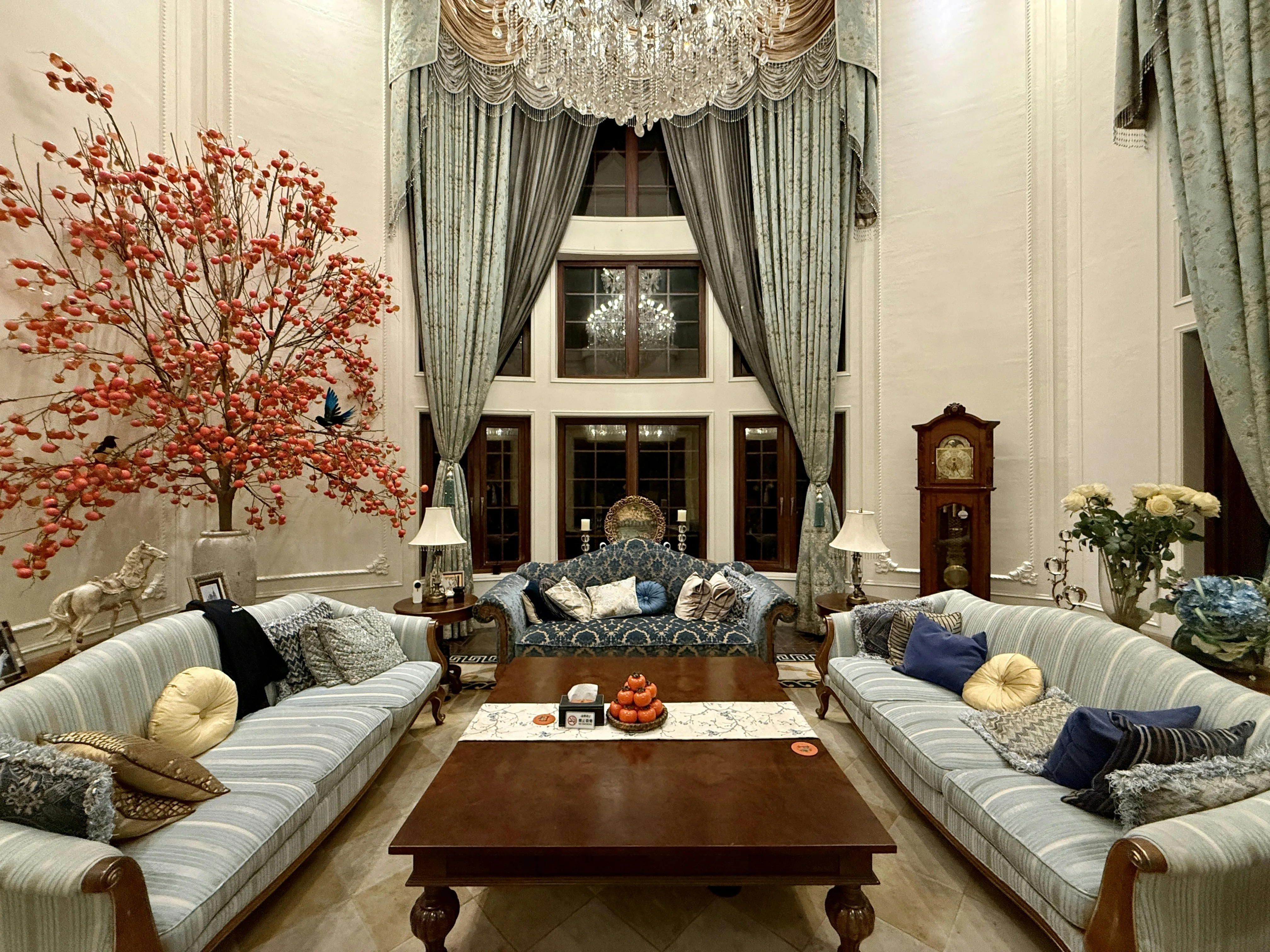 A classic salon with a chandelier, tall windows, and upholstered seating